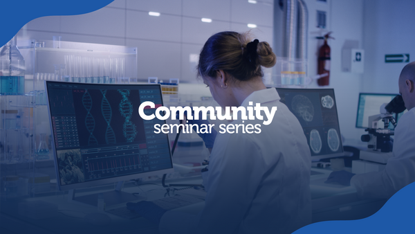 person in lab coat looking at DNA on a computer monitor